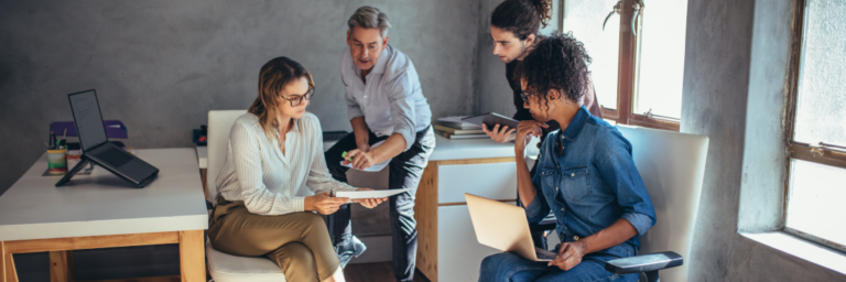 Group of four professionals in a discussion at a casual office setting, utilizing Biteable video maker.